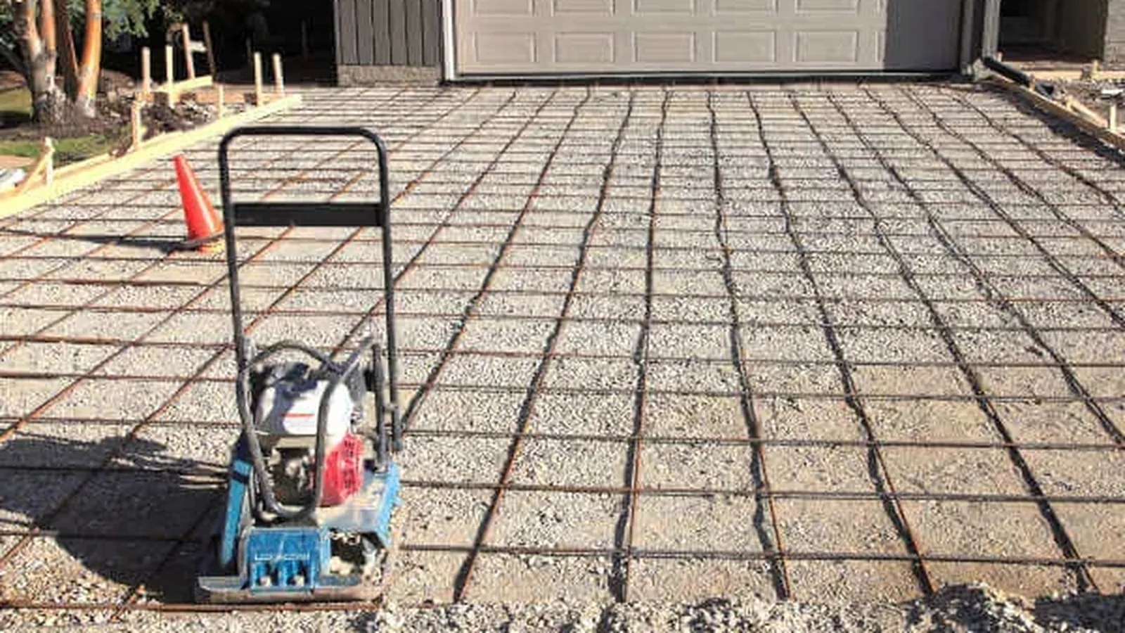 Steel reinforcement mesh laid over a compacted base with a plate compactor, ready for a concrete pour
