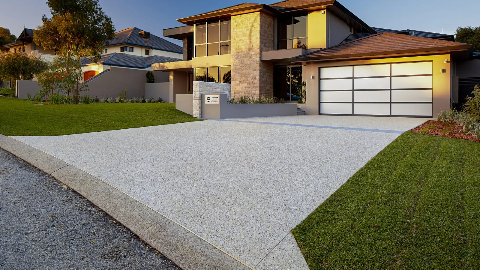Newly finished concrete driveway outside a modern home at dusk