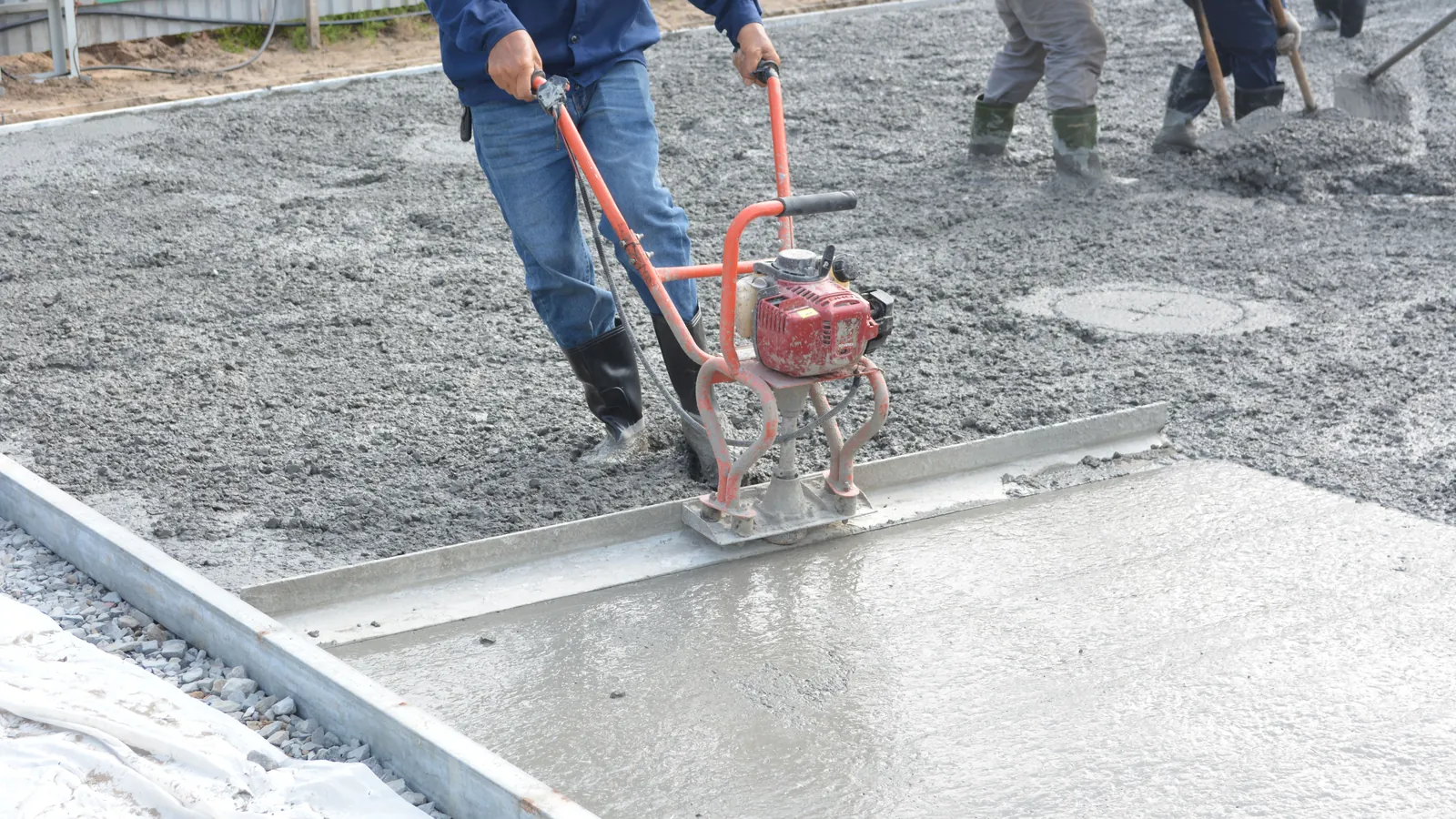 Construction workers levelling and finishing freshly poured concrete