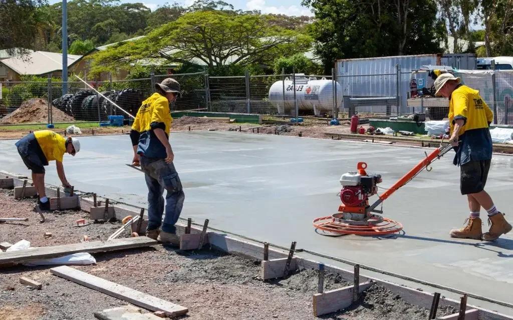 Concreting crew power-trowelling and finishing a freshly poured concrete slab